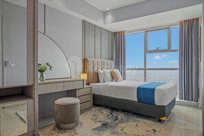 A modern hotel room with a large bed, a bedside table, a mirror, and a view of the city through large windows. - Ardana by Kozystay - Tunjungan (Surabaya)