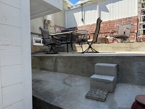 Eine Außenpatio mit Tisch und Stühlen, einem Betonpodest und einer Ziegelwand.