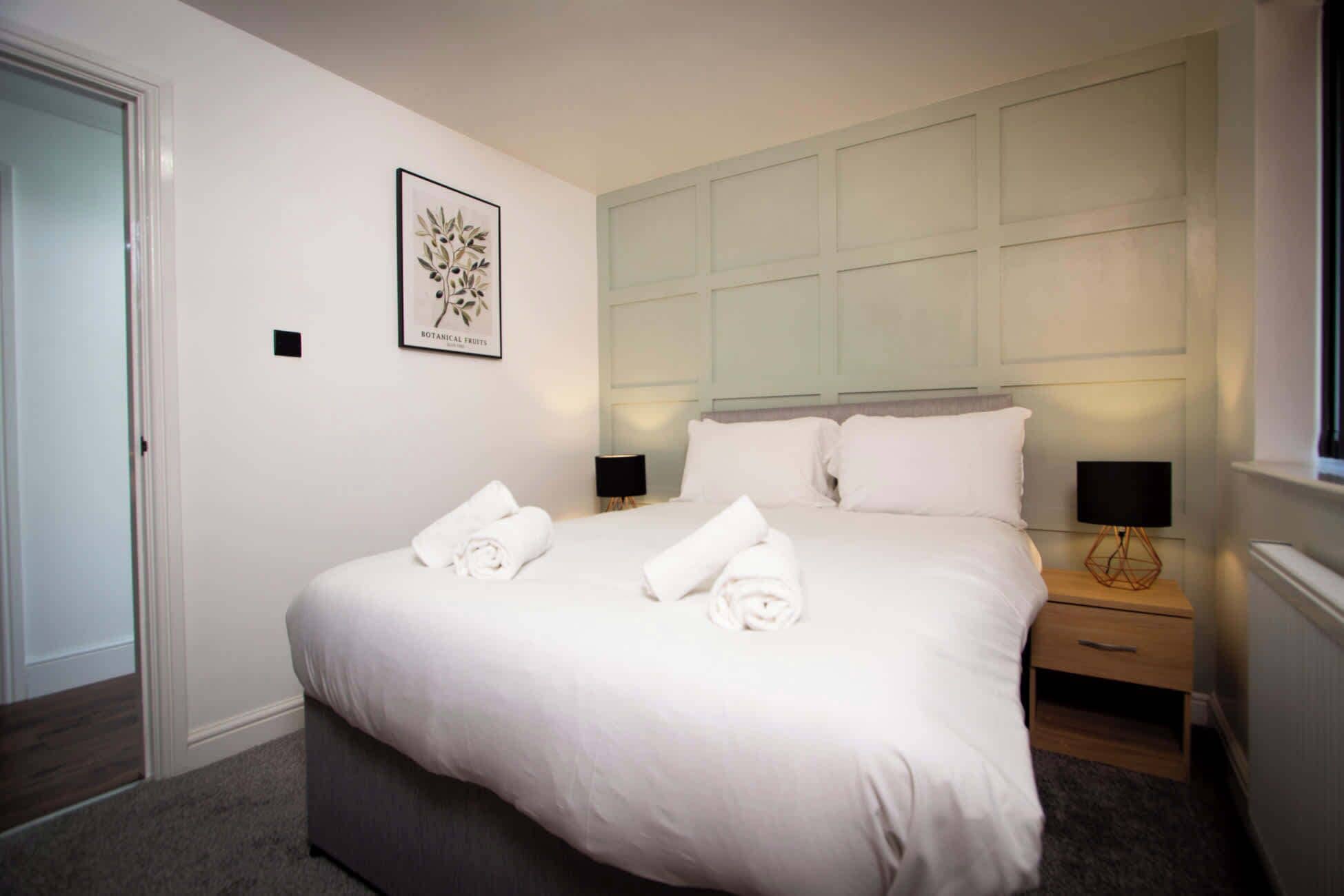 A hotel room with a large bed, two bedside tables, a wall-mounted artwork, and a window.