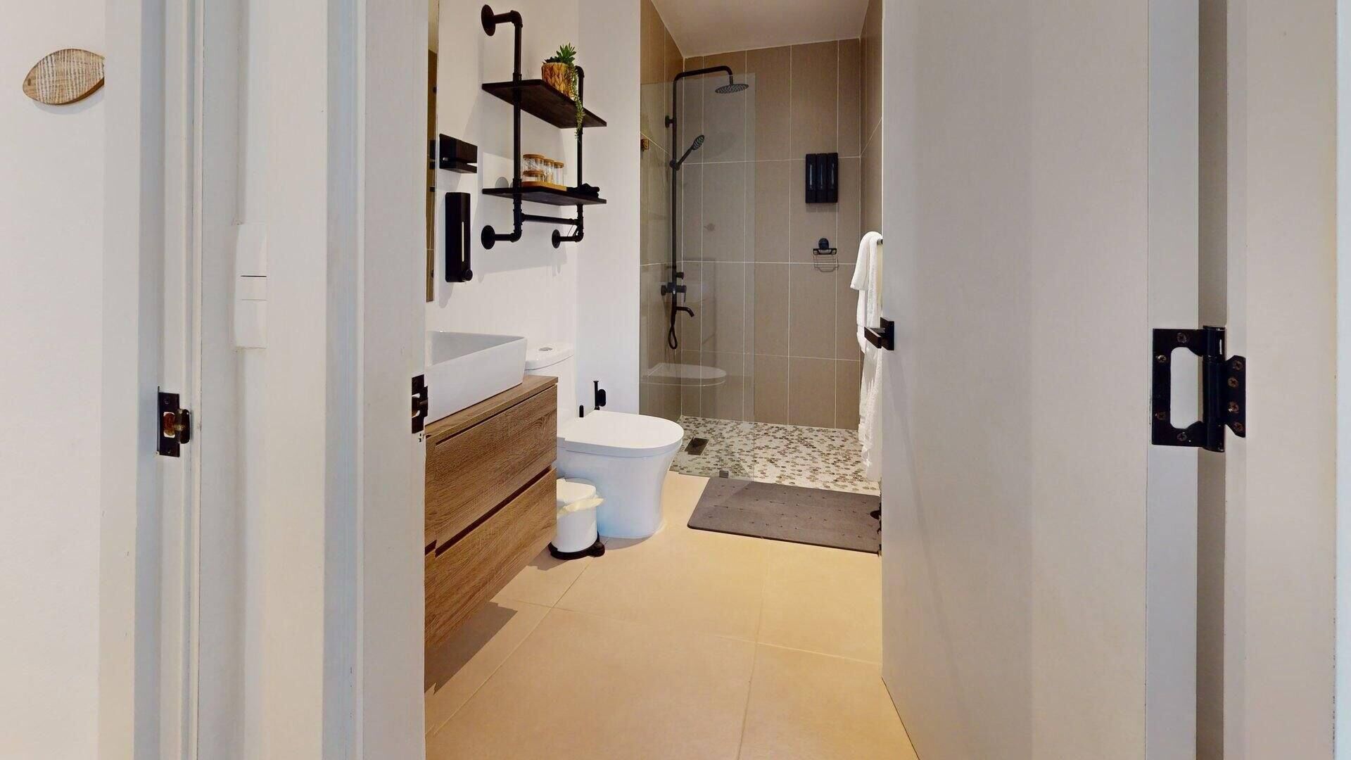 Uma casa de banho moderna com sanita, lavatório e chuveiro.