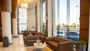 Un vestíbulo moderno con zona de estar, ventanas amplias y vista a la calle.