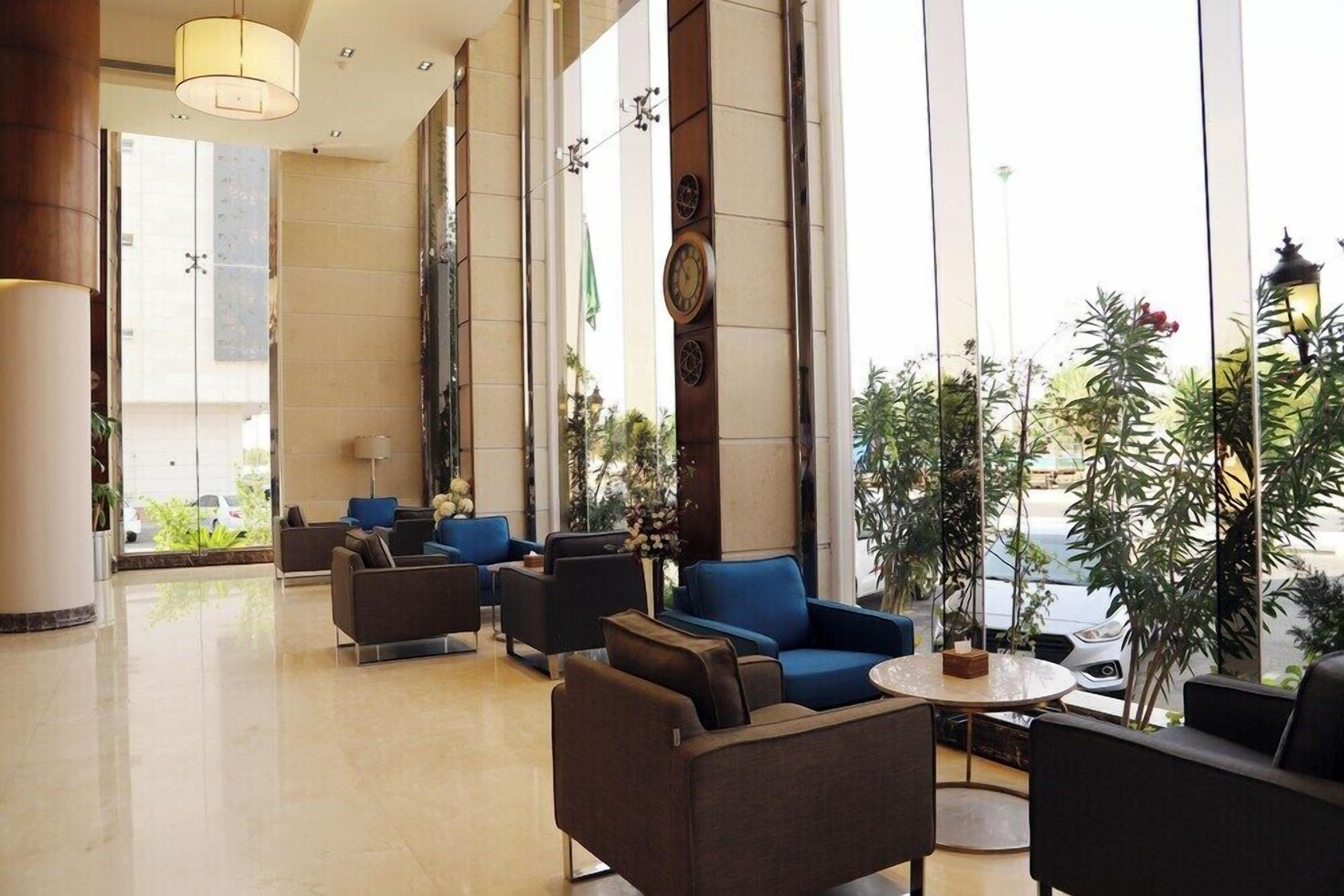 Vestíbulo de hotel con zonas de estar, ventanas amplias y elementos decorativos.
