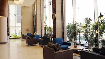 Vestíbulo de hotel con zonas de estar, ventanas amplias y elementos decorativos.