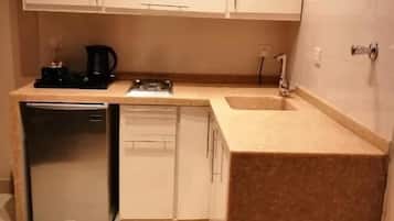 A compact kitchen with a refrigerator, dishwasher, and a coffee maker.