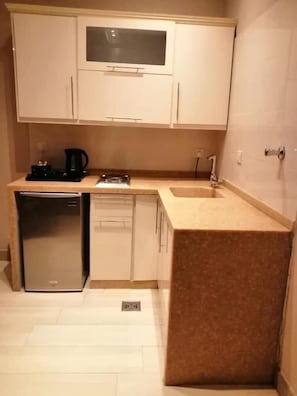 A compact kitchen with a refrigerator, dishwasher, and a coffee maker. - Banan Hotel (Tabuk)