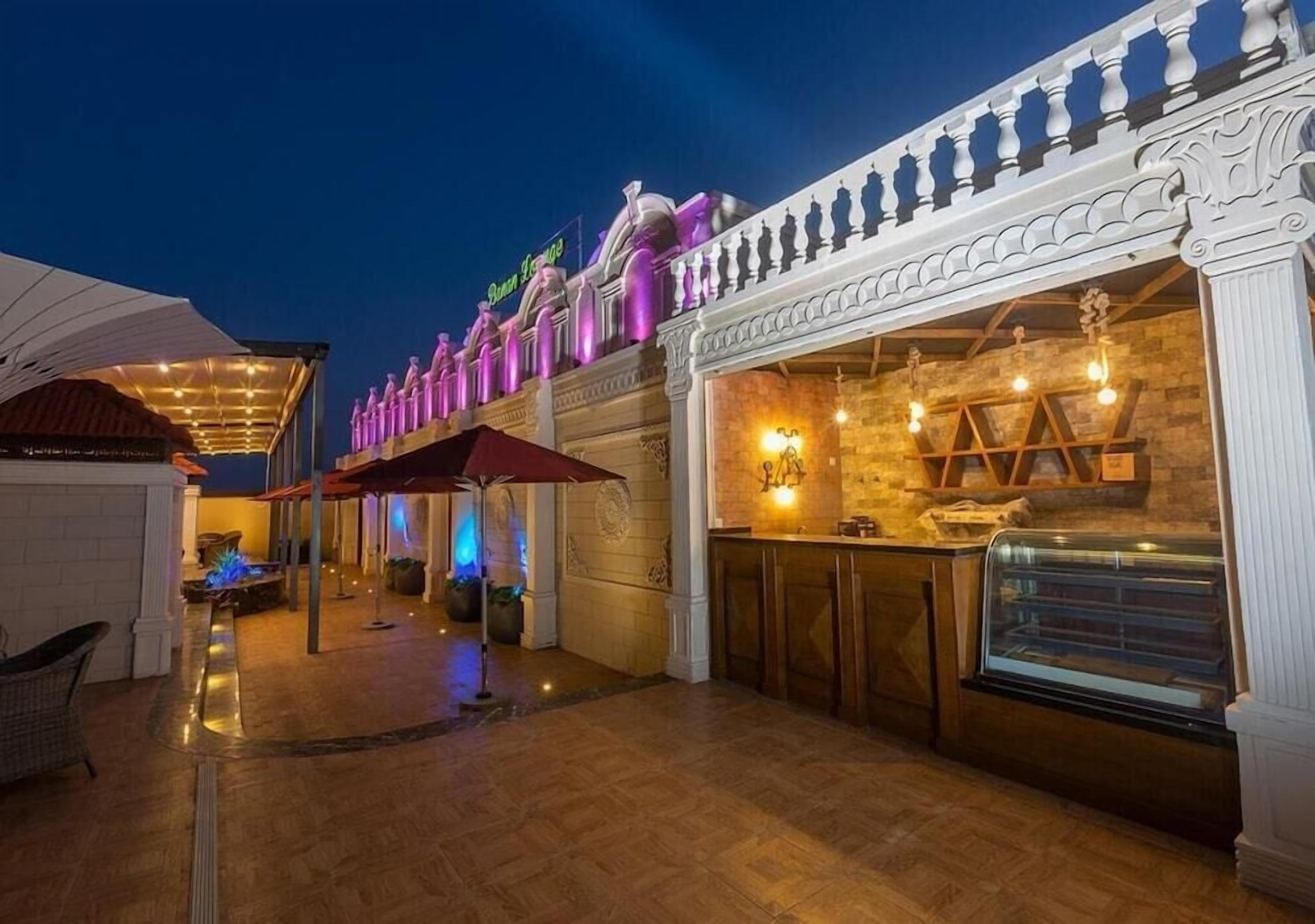 An outdoor dining area with a bar, a covered seating area, and a building with a decorative facade.