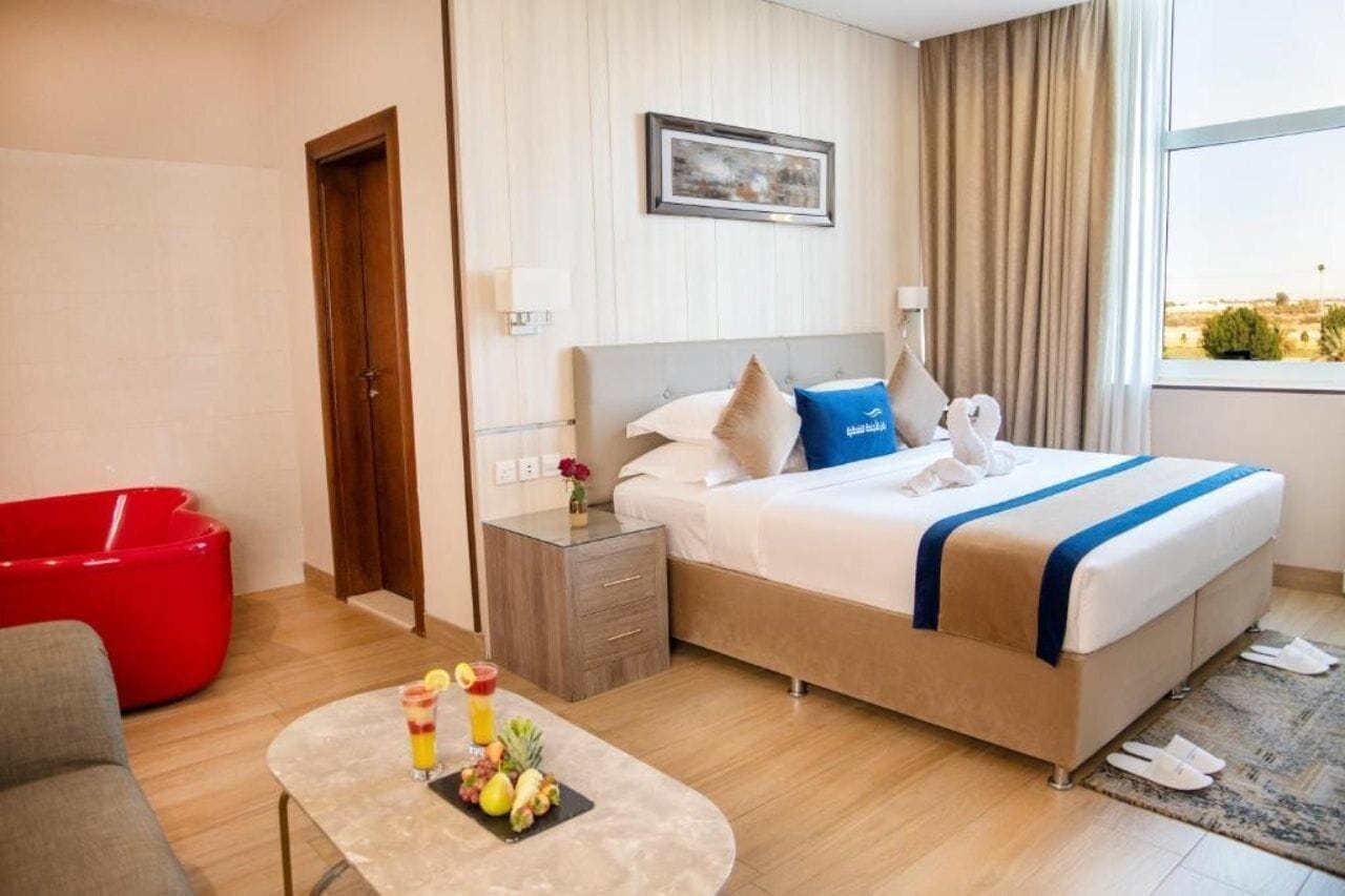 Habitación de hotel con cama, mesita de noche y una silla roja.