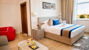Habitación de hotel con cama, mesita de noche y una silla roja.