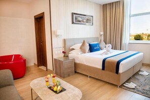 A hotel room with a bed, bedside table, and a red chair. - Banan Hotel (Tabuk)