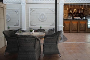 An outdoor seating area with wicker furniture, a round table, and decorative wall panels. - Banan Hotel (Tabuk)