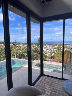 A room with large windows overlooking a swimming pool and a residential area.
