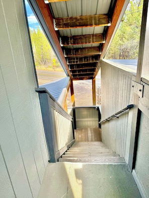 A wooden staircase leading to a covered outdoor area with a metal roof.