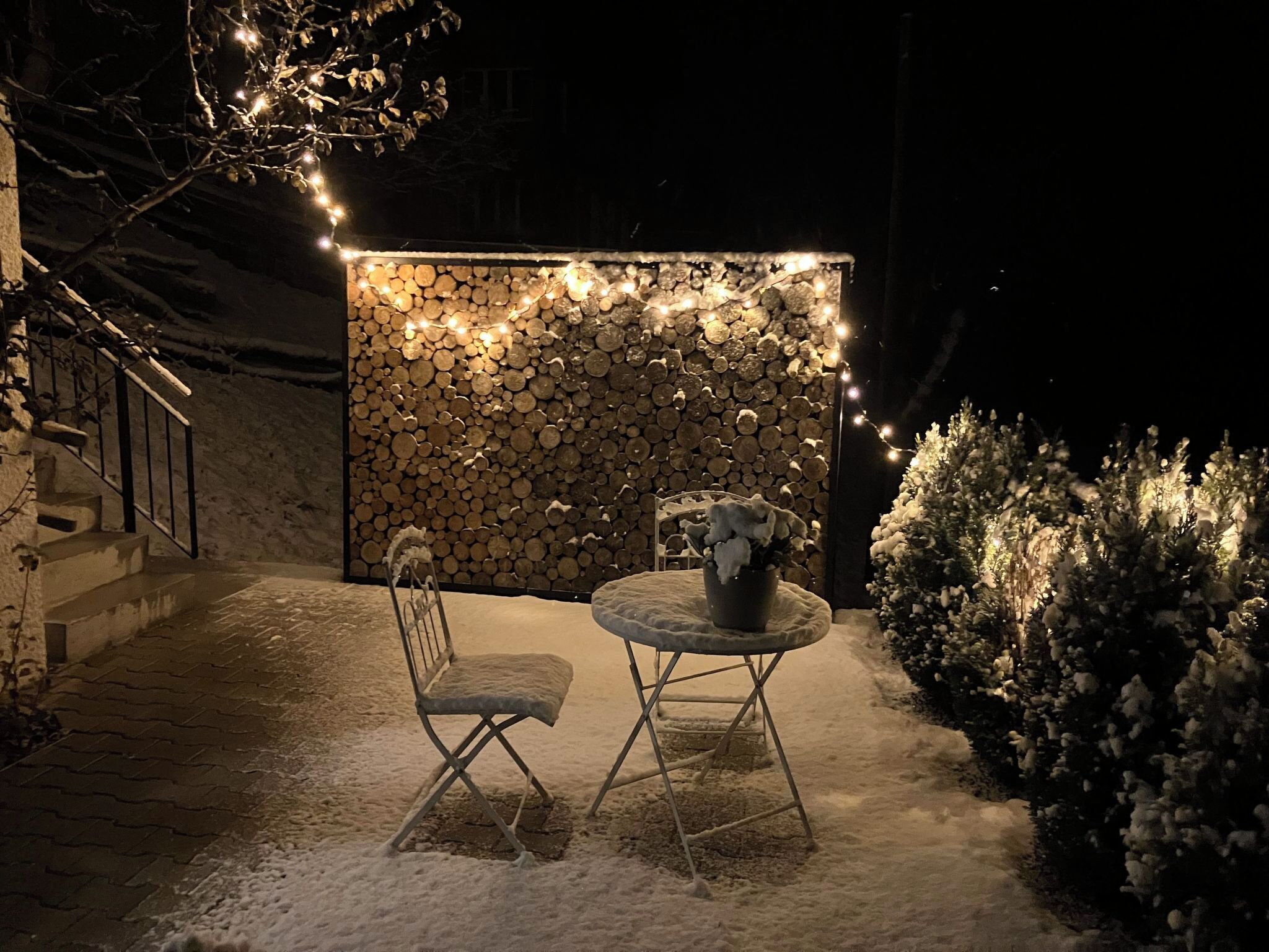An outdoor seating area with a stone wall backdrop, a table, and chairs.