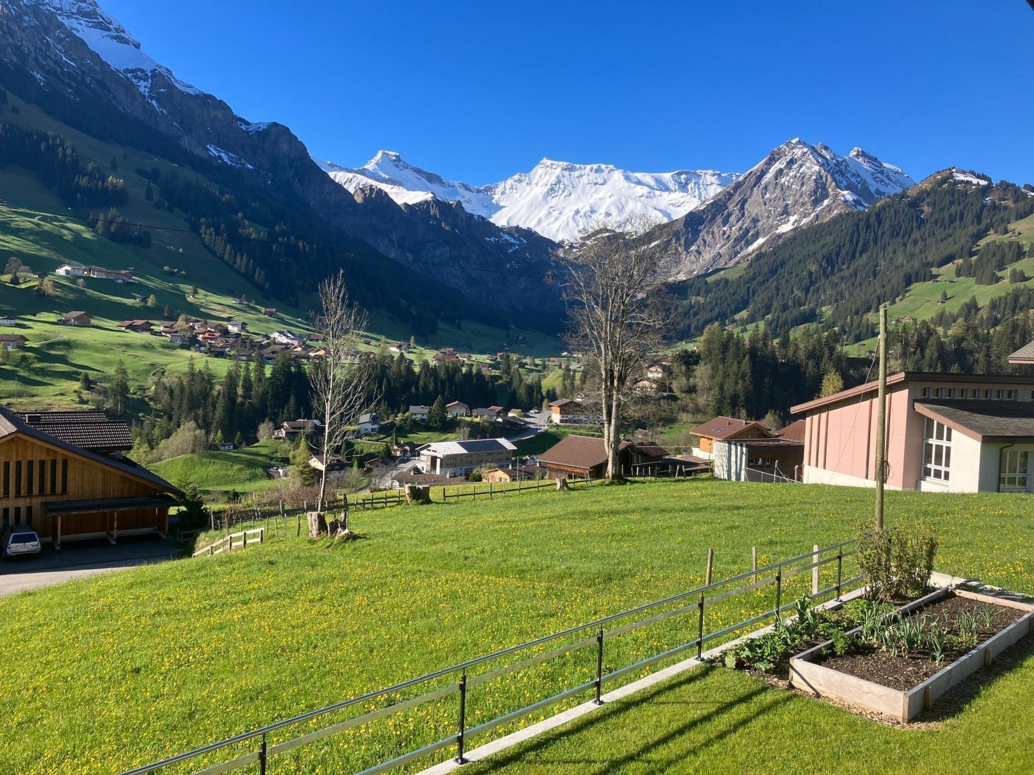 A rural village with houses, a field, and mountains in the background.