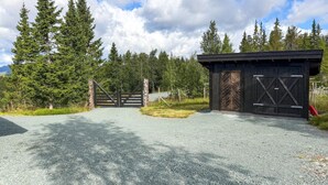 A gravel driveway leading to a wooden gate and a black building with a herringbone door. - Gorgeous home in Vinje with WiFi (Vinje)