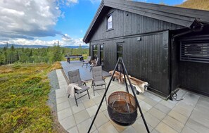 Eine Holzterrasse mit Gartenmöbeln, einer Schaukel und einem Hund.