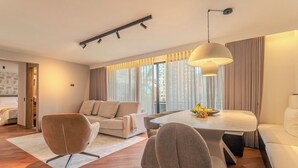Una sala moderna con un sofá, sillas, una mesa de comedor y un gran ventanal con cortinas.