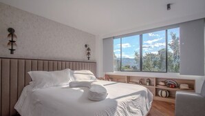 Un dormitorio moderno con una cama grande, vistas al exterior y un cabecero de madera.