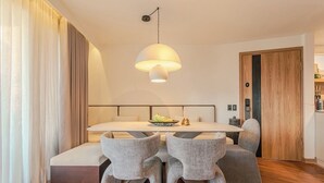 Un comedor moderno con una mesa central, sillas tapizadas de gris y una lámpara colgante.