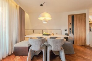 A modern dining area with a central table, grey upholstered chairs, and a pendant light.