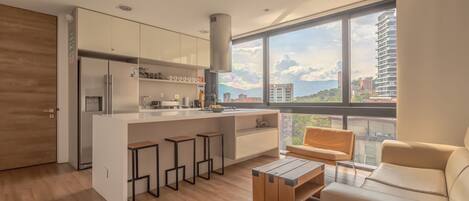 Cocina moderna con una isla central, taburetes de bar y un ventanal con vistas a la ciudad.