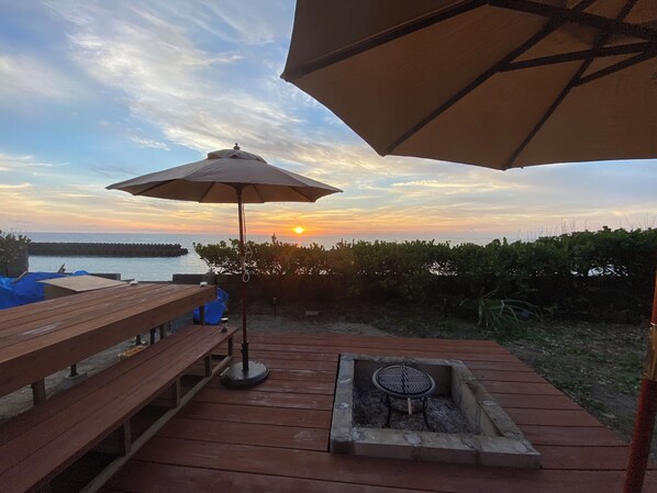 A wooden deck with a barbecue pit and an umbrella.