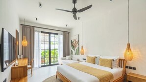 A modern bedroom with a large bed, a ceiling fan, a dining area, and a view of greenery outside. - Ubud's Best 2BR w Huge Rooftop & Pool by Ricefield (Ubud)