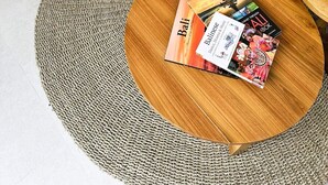 A modern living room with a round wooden coffee table, a flat-screen TV, and a small wooden side table. - Ubud's Best 2BR w Huge Rooftop & Pool by Ricefield (Ubud)