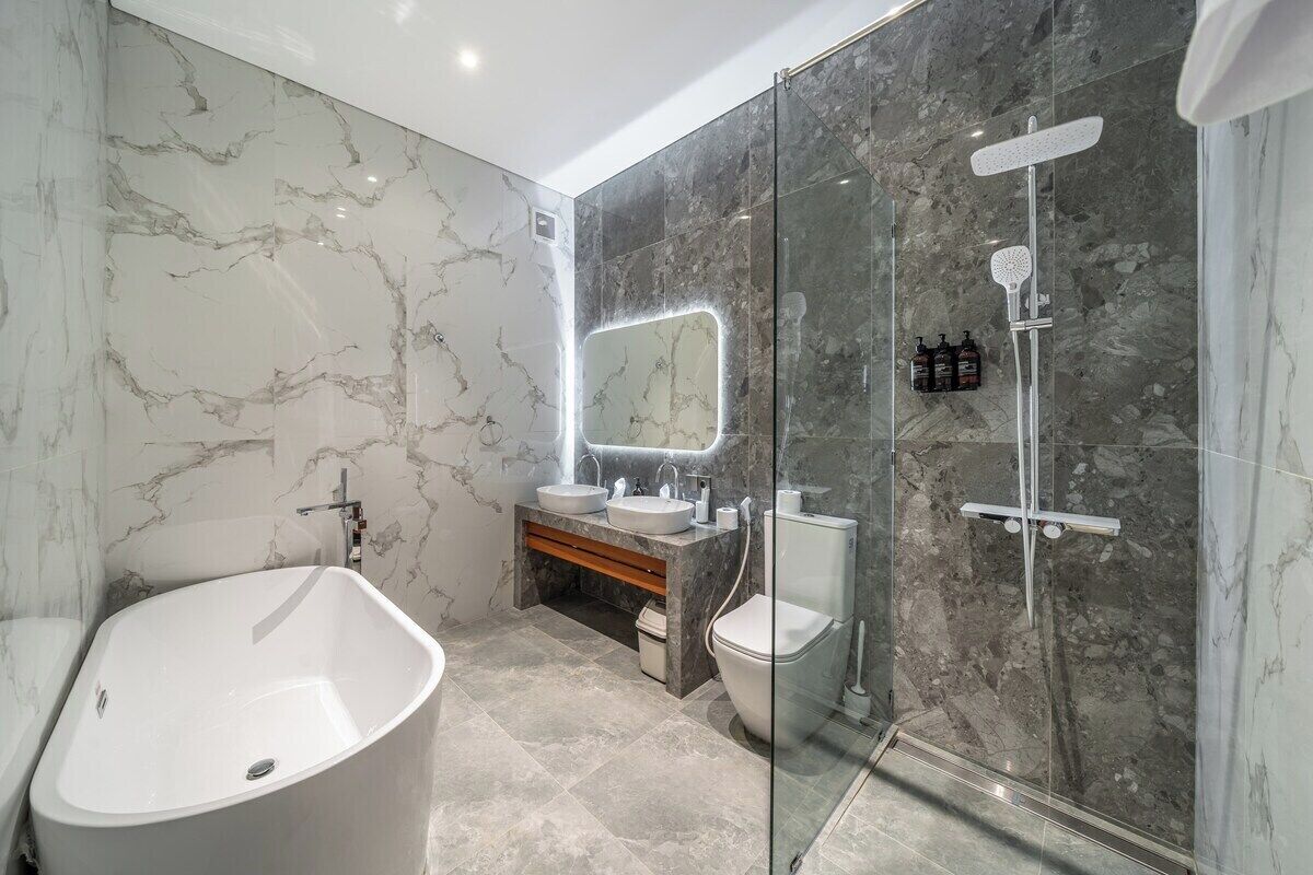 Ein modernes Badezimmer mit freistehender Badewanne, einer Glasdusche und einem Waschtisch mit Spiegel.