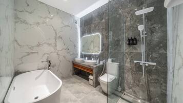 Ein modernes Badezimmer mit freistehender Badewanne, einer Glasdusche und einem Waschtisch mit Spiegel.