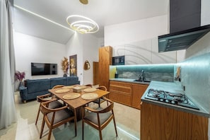 A modern kitchen with a gas stove, wooden cabinets, and a built-in microwave. - Modern 3BR near Pandawa Beach w Private Pool&Patio (Badung Regency)