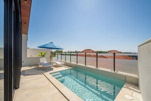 A rooftop swimming pool with a clear view of the surrounding buildings and a blue umbrella. - Modern 3BR near Pandawa Beach w Private Pool&Patio (Badung Regency)