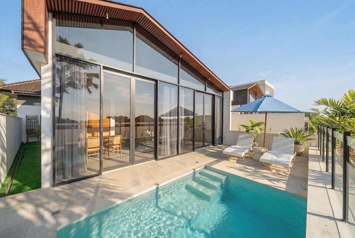 Une maison moderne dotée d’une piscine, de grandes baies vitrées et d’un espace salon extérieur.