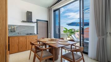 Eine moderne Küche mit Essbereich, großen Fenstern und Blick ins Freie.