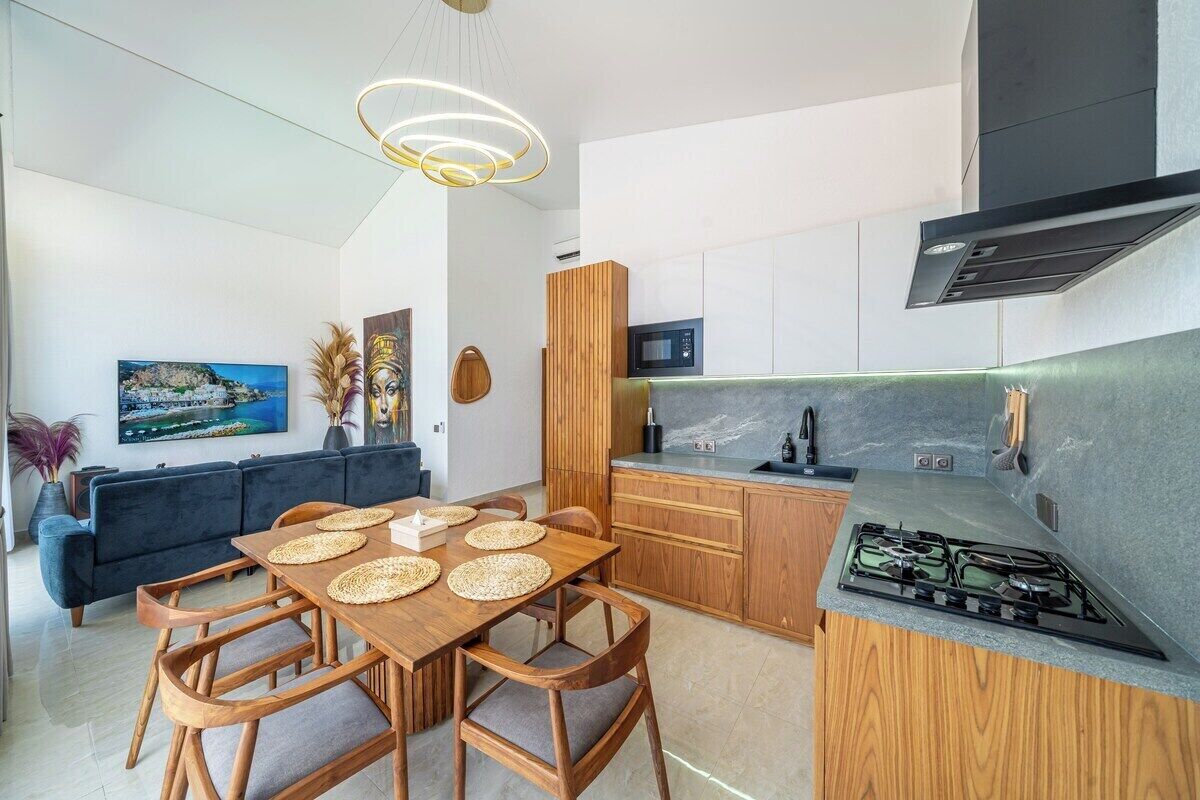 Une cuisine moderne équipée d’une cuisinière à gaz, de meubles en bois et d’un coin repas avec une table et des chaises.