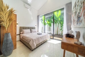 A modern bedroom with a bed, a wooden bedside table, a large vase, and a view of greenery through the window.