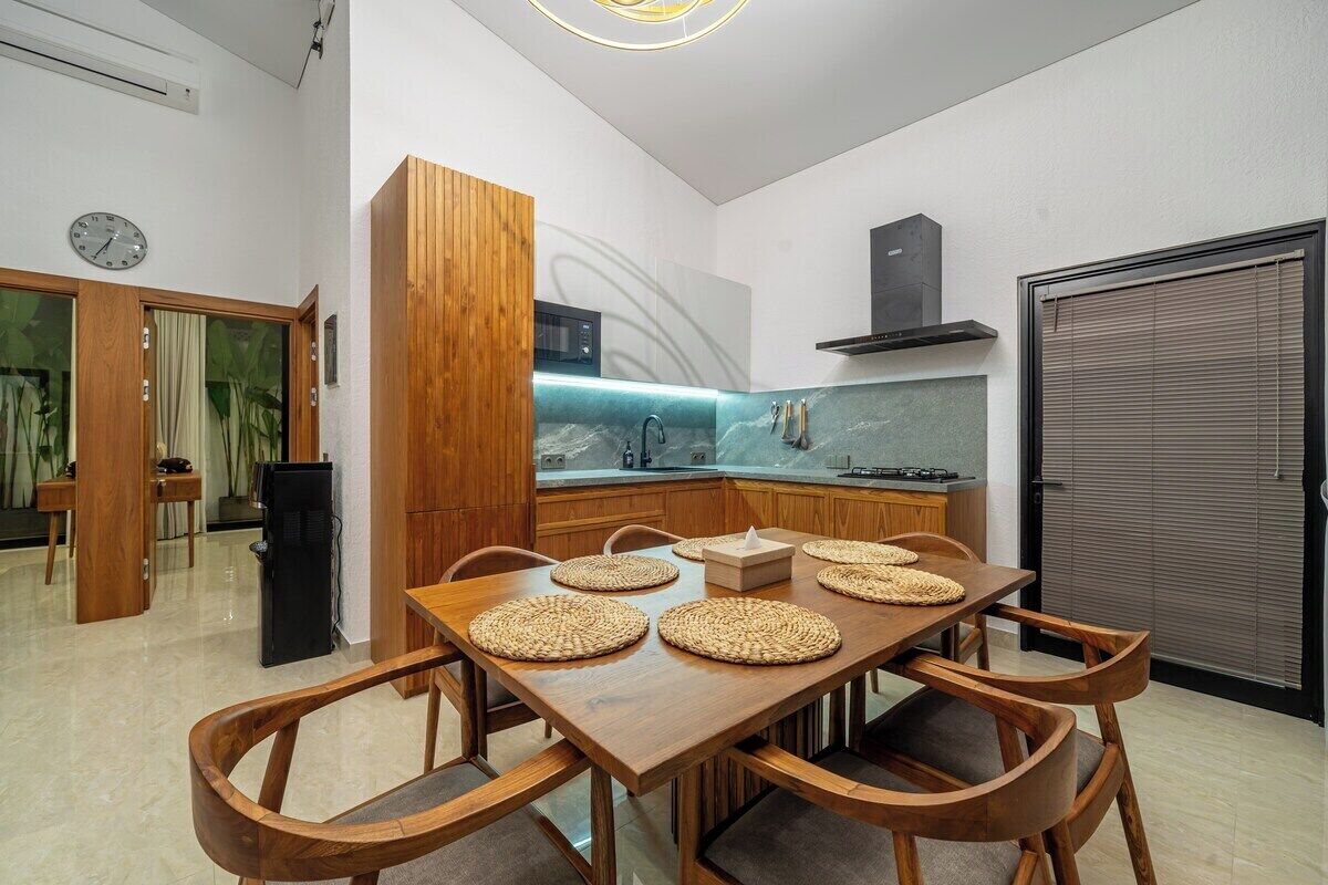 Eine moderne Küche mit einem Holzespeisetisch, Stühlen und einer eingebauten Mikrowelle.