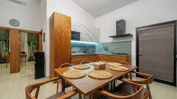 Eine moderne Küche mit einem Holzespeisetisch, Stühlen und einer eingebauten Mikrowelle.