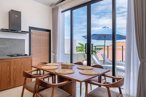 A modern kitchen with a gas stove, wooden cabinets, and a large window overlooking a terrace. - Modern 3BR near Pandawa Beach w Private Pool&Patio (Badung Regency)