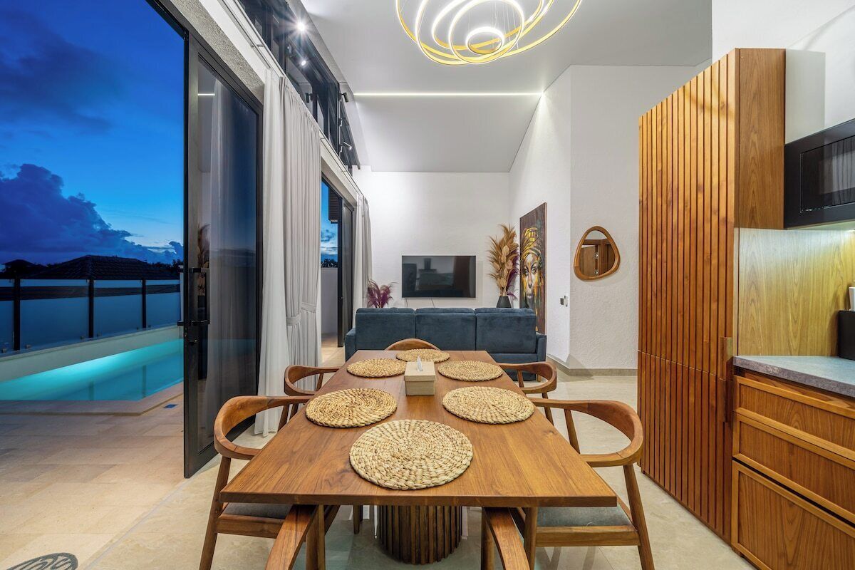 A modern interior with a dining area, kitchen, and a balcony with a pool.