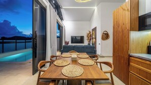 Un interior moderno con comedor, cocina y un balcón con piscina.