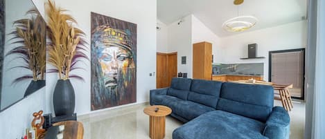 Una sala de estar moderna con un sofá azul, una mesa de centro de madera y un cuadro en la pared.