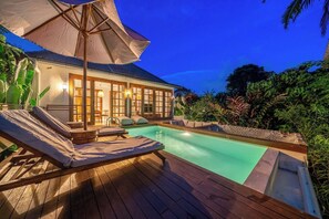 A poolside area with a lounge chair and umbrella, surrounded by lush greenery. - Hidden 3BR Oasis in Serene Ubud w Huge Pool+Patio (Gianyar Regency)