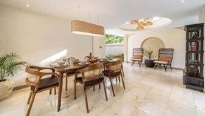 A dining area with a round table, wooden chairs, and a hanging light fixture. - Boho 2BR w Pool+Patio+Garden in Peaceful Ubud (Gianyar Regency)