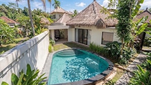 A pool surrounded by a white wall and tropical vegetation, with a thatched-roof structure in the background. - Boho 2BR w Pool+Patio+Garden in Peaceful Ubud (Gianyar Regency)