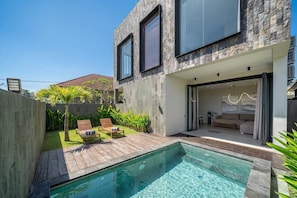 A modern house with a swimming pool, a patio with lounge chairs, and a well-maintained garden. - Grey Stones - Designer 2BR Villa w Rooftop, Pool & Beach Nearby (Badung Regency)