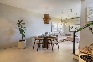 A modern living room with a round dining table, sofas, and potted plants.