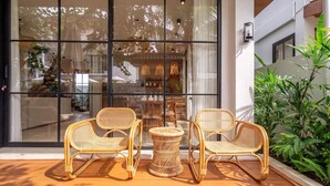 A glass door entrance with wicker furniture outside. - Cozy 3BR in Ubud w Bathtubs, Ricefield Views, Pool (Tegallalang)