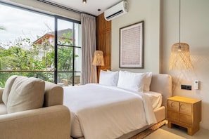 Ein Hotelzimmer mit einem Bett, einem Schlafsofa, einem Nachttisch und einem großen Fenster mit Blick auf Grünflächen.