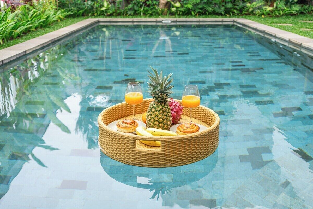 Ein Pool mit einem schwimmenden Korb voller Früchte und Getränke.